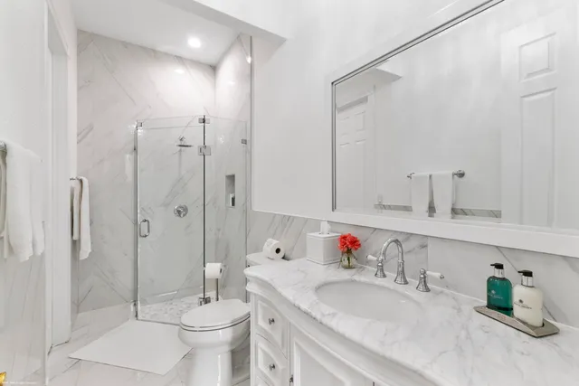 a bathroom with a granite countertop sink a toilet and shower