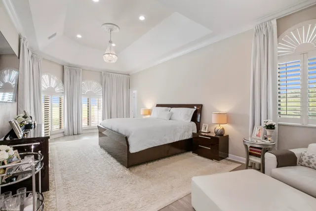 a spacious bedroom with a bed a couch and large windows