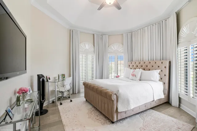 a bedroom with a bed flat screen tv and windows