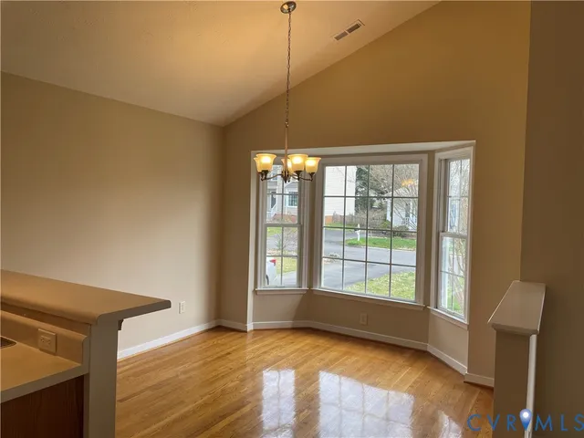 a view of an empty room with glass door and wooden floor