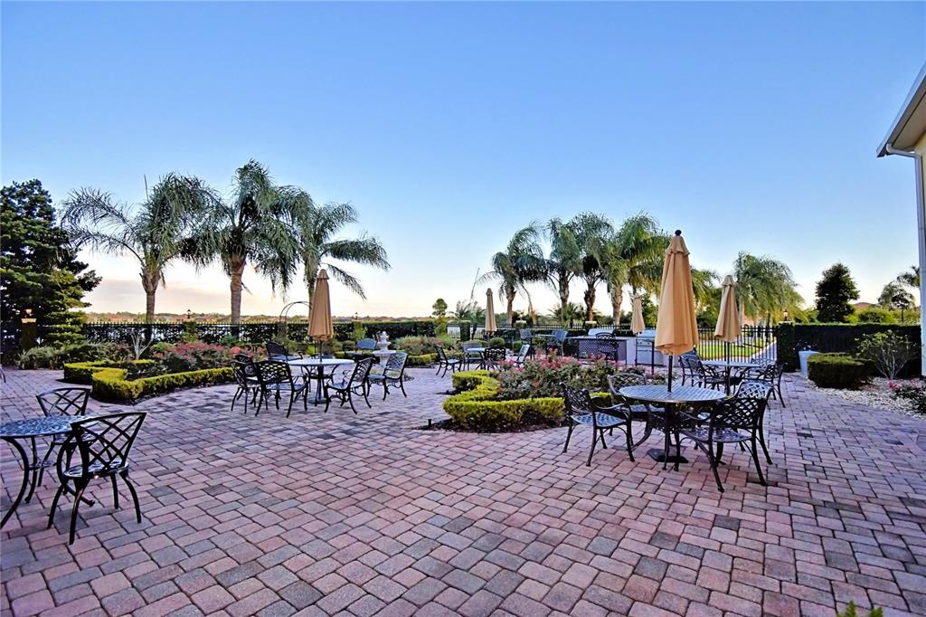 4188 Muirfield Loop Lake Wales, FL 33859 - Photo 63 of 74 a view of a patio with a dining table and chairs with plants and palm trees