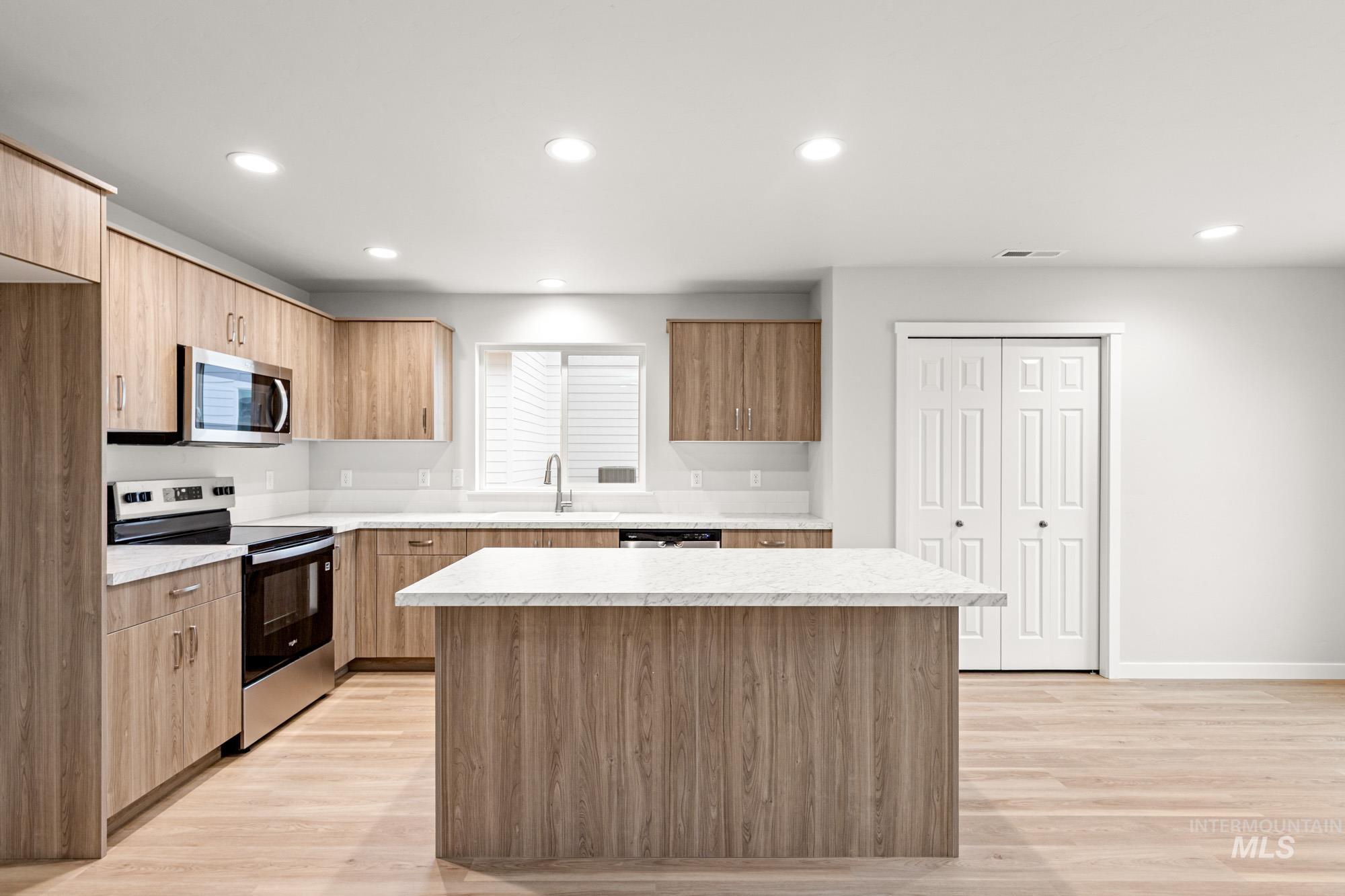 4287 South Red Sox Way Nampa, ID 83686 - Photo 3 of 22 Kitchen featuring stainless steel appliances, modern cabinets, light countertops, light wood-style flooring, and a center island