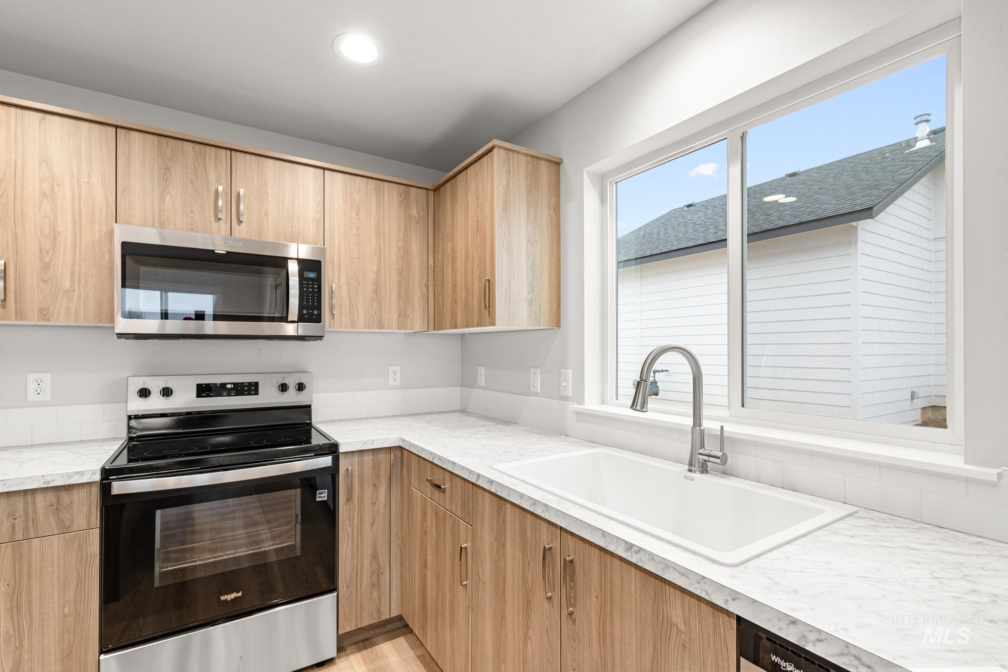 4287 South Red Sox Way Nampa, ID 83686 - Photo 6 of 22 Kitchen featuring appliances with stainless steel finishes, light countertops, light brown cabinets, modern cabinets, and recessed lighting