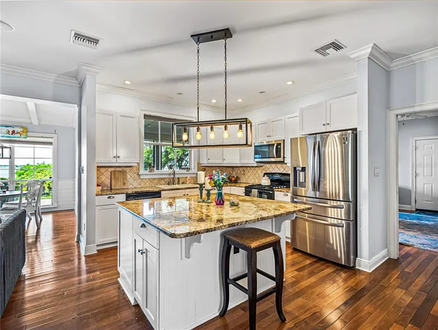 a kitchen with refrigerator a stove and wooden floor