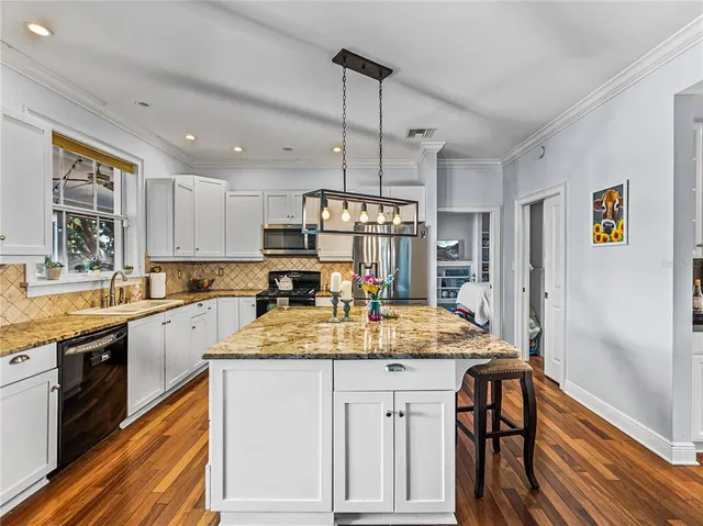 a kitchen with kitchen island granite countertop wooden cabinets and white appliances