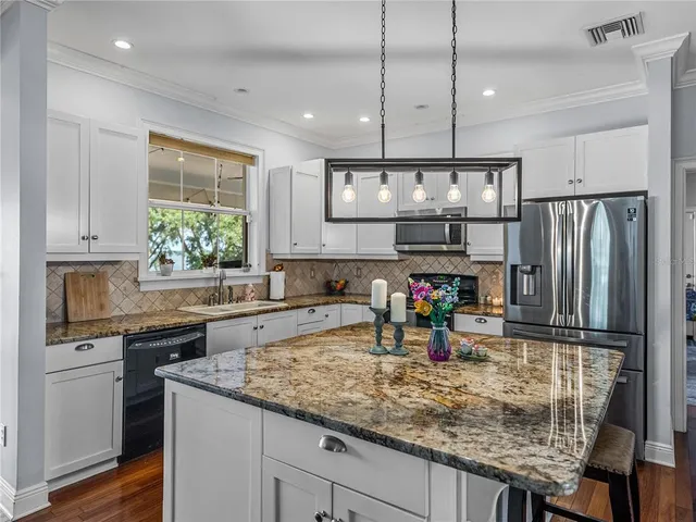 a kitchen with stainless steel appliances granite countertop a sink refrigerator and cabinets