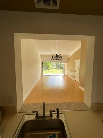 a view of an empty room with a chandelier fan