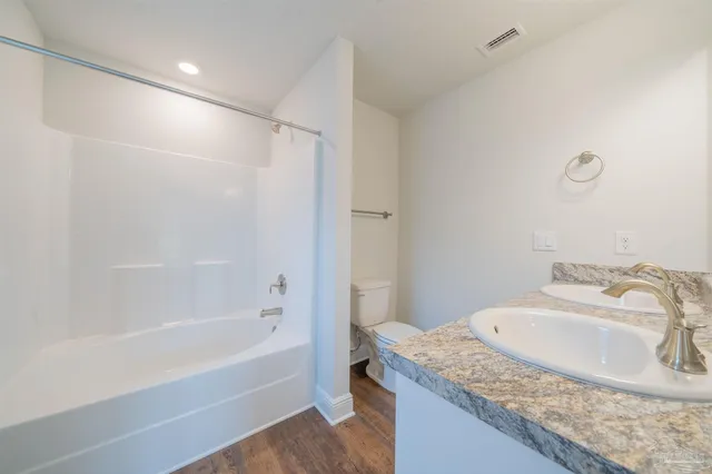 a bathroom with a granite countertop sink a mirror and a bath tub
