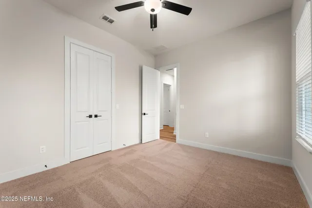an empty room with ceiling fan and window
