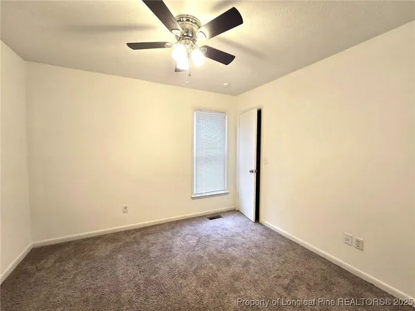 an empty room with a ceiling fan and a window