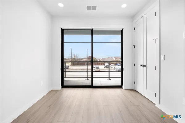 an empty room with wooden floor and windows