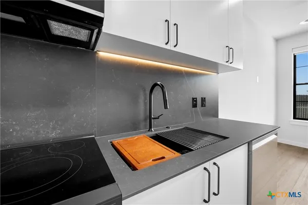 a close view of a sink a stove and kitchen counter top space