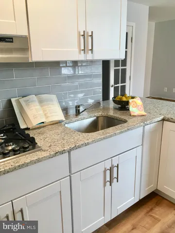 a kitchen with granite countertop white cabinets and a sink