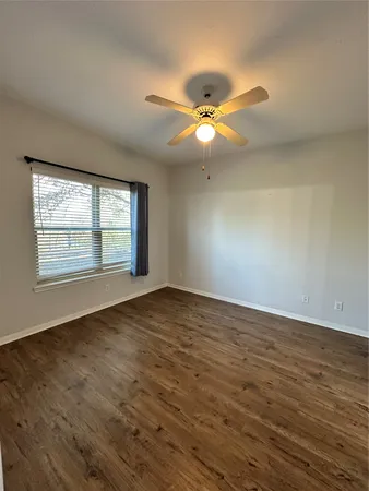 an empty room with wooden floor fan and windows