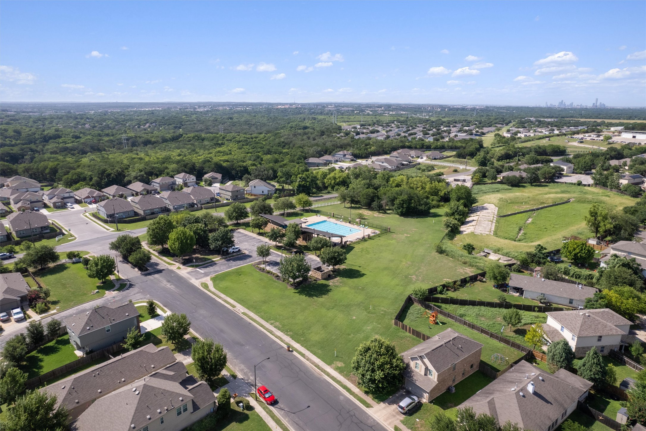5825 Silver Screen Drive Austin, TX 78747 - Photo 30 of 40 An aerial perspective reveals a vibrant neighborhood with a refreshing pool, ample green spaces, and a distant city skyline.