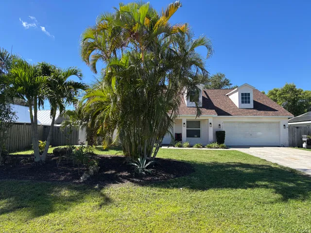 a view of a house with a yard and palm tree