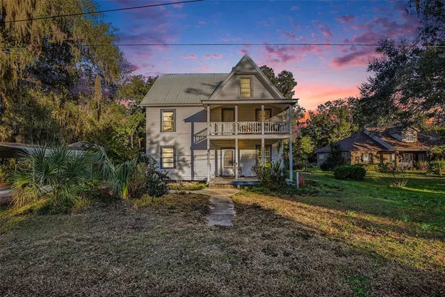a view of a big house with a big yard and large trees
