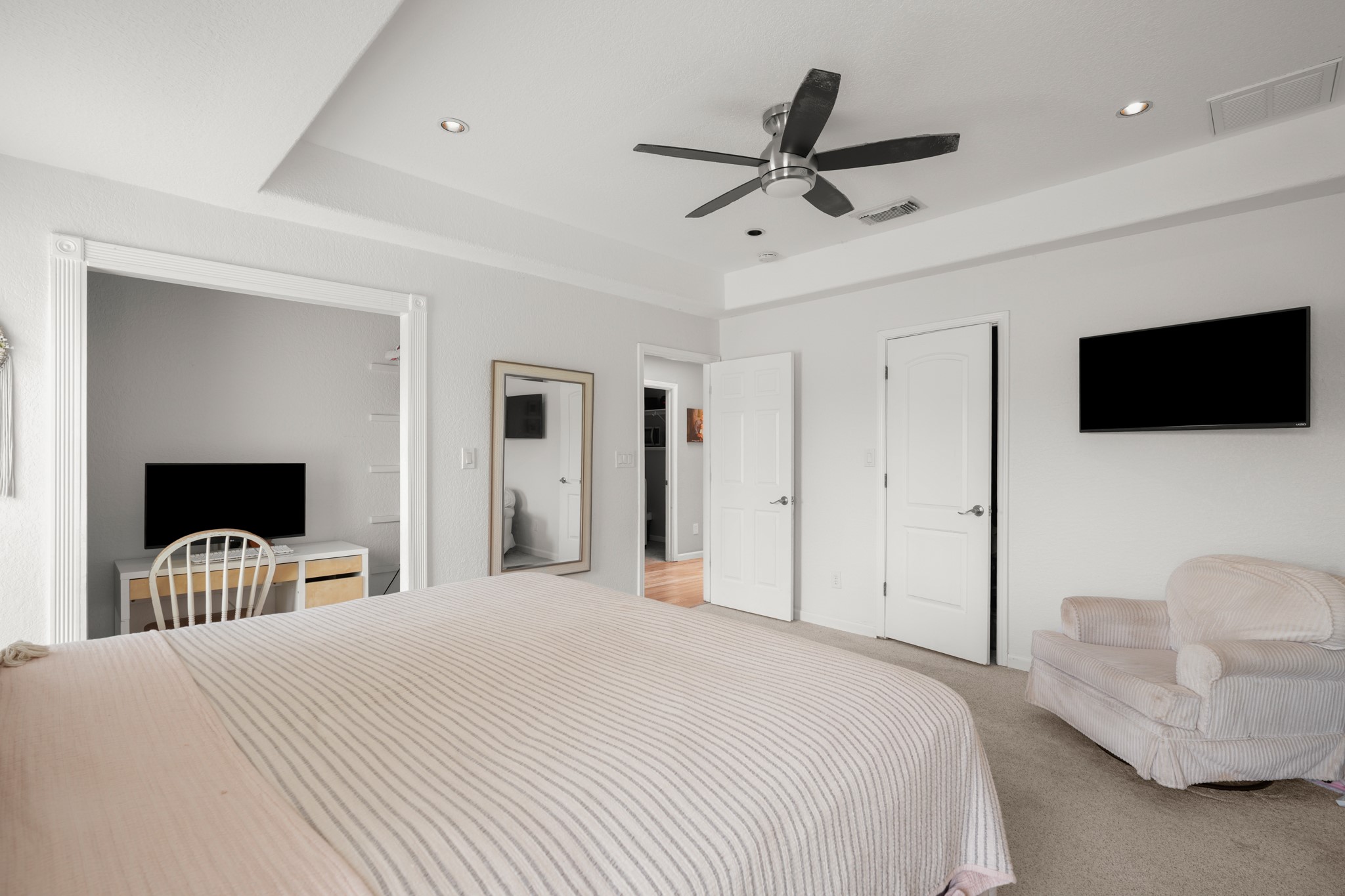 9725 Bock Road Buda, TX 78610 - Photo 21 of 32 A tranquil primary bedroom features plush carpeting, a modern ceiling fan, and ample natural light from the open doorway.