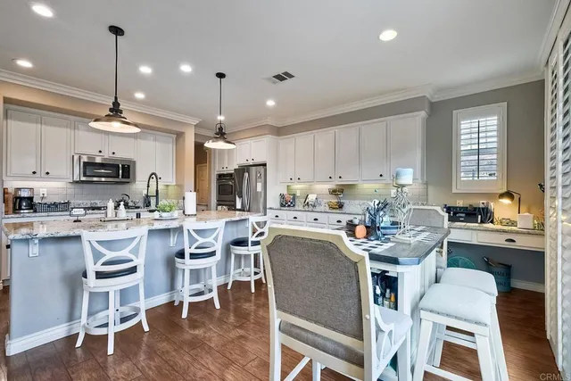 a view of a patio with couches table and chairs under an umbrella with a barbeque