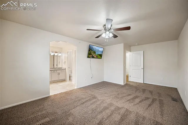a view of empty room with wooden floor and ceiling fan