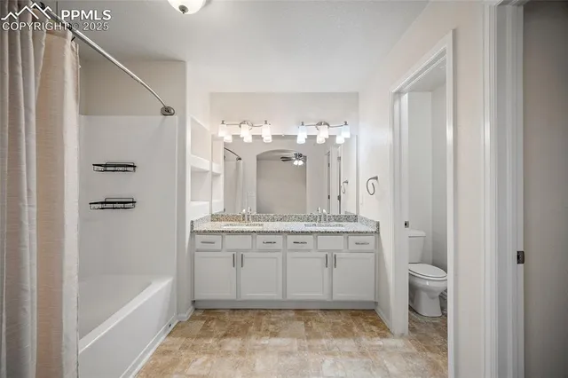 a spacious bathroom with a granite countertop sink a toilet and shower
