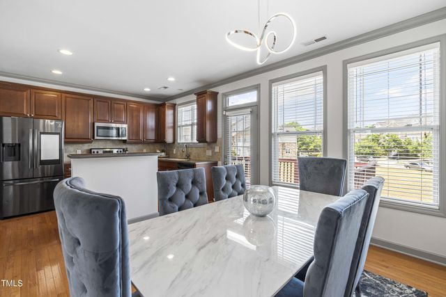 a kitchen with stainless steel appliances granite countertop a stove a refrigerator a sink dishwasher a dining table and chairs with wooden floor