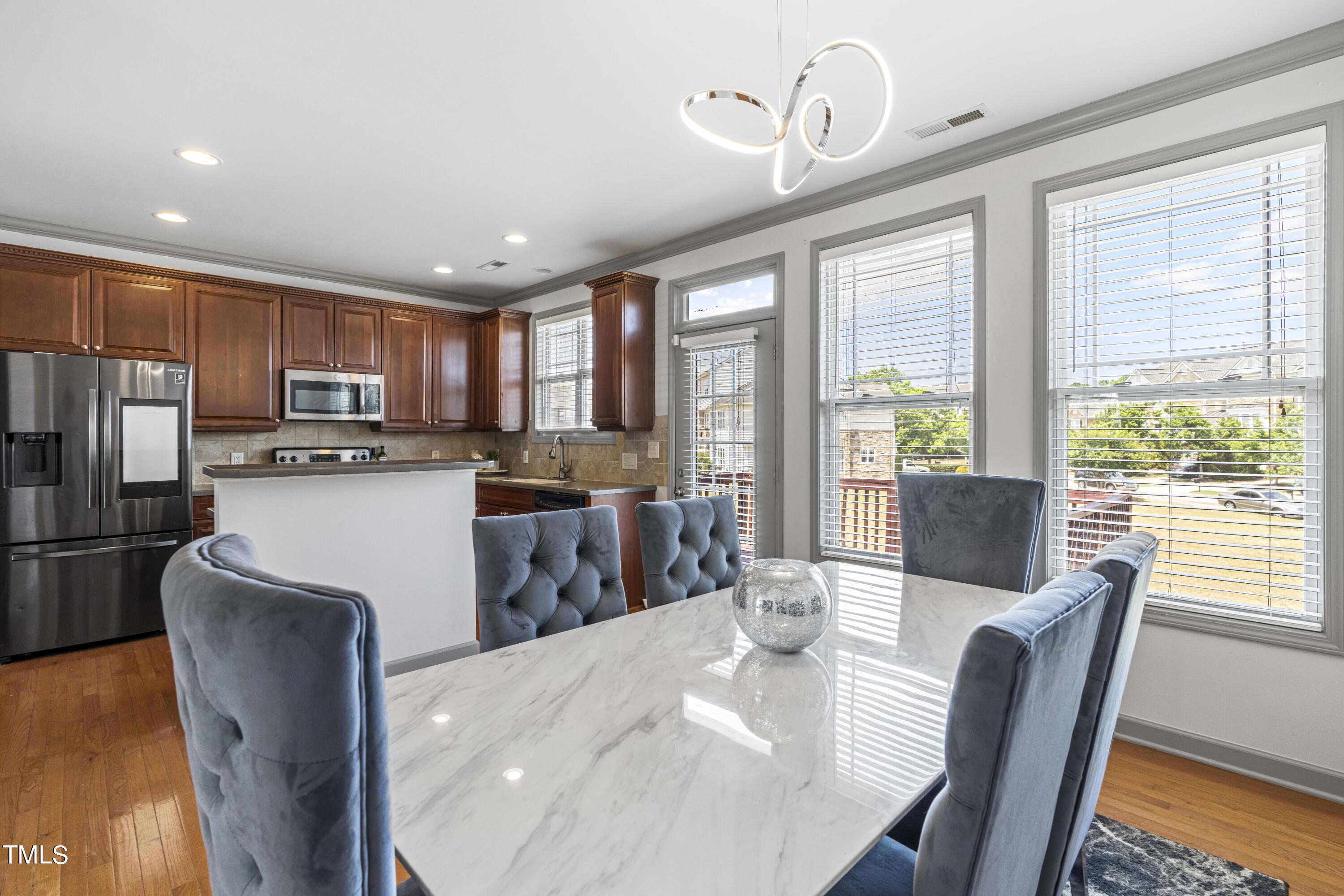 4419 Iyar Way Wake Forest, NC 27587 - Photo 12 of 26 a kitchen with stainless steel appliances granite countertop a stove a refrigerator a sink dishwasher a dining table and chairs with wooden floor