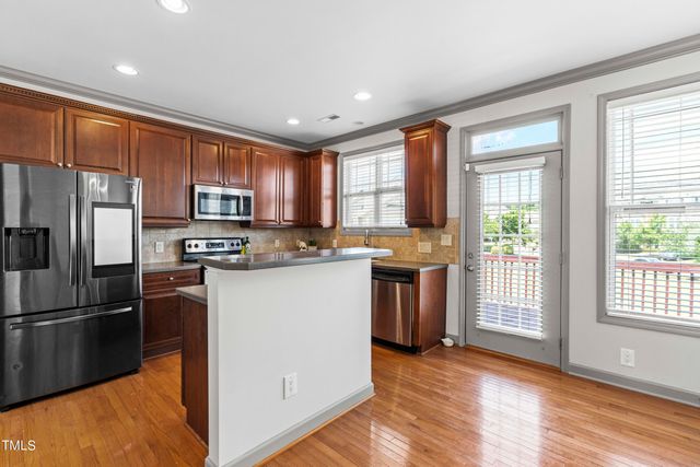 a kitchen with stainless steel appliances granite countertop a refrigerator a stove top oven a sink and dishwasher with wooden floor