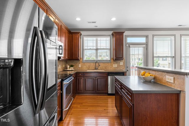 a kitchen with stainless steel appliances granite countertop a refrigerator a sink a stove and island