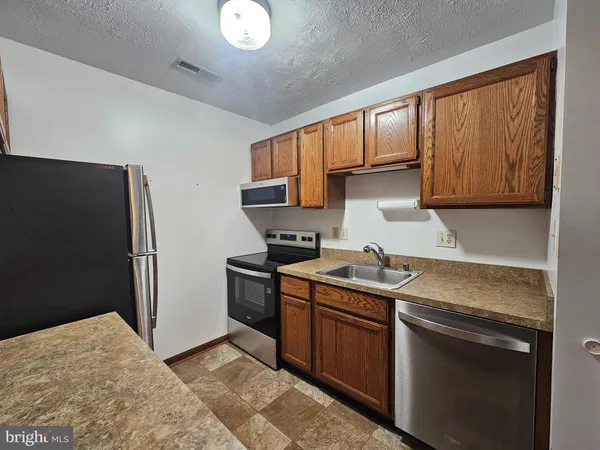 a kitchen with stainless steel appliances granite countertop a stove a refrigerator and a sink