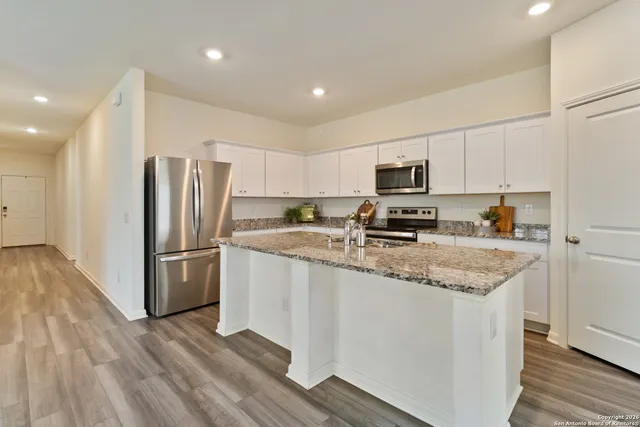 a kitchen with granite countertop a refrigerator and a stove top oven