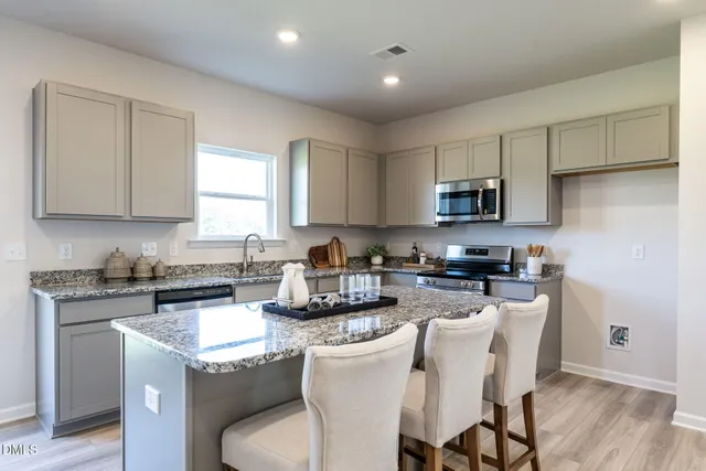 a kitchen with stainless steel appliances granite countertop a sink a stove a microwave a refrigerator and cabinets