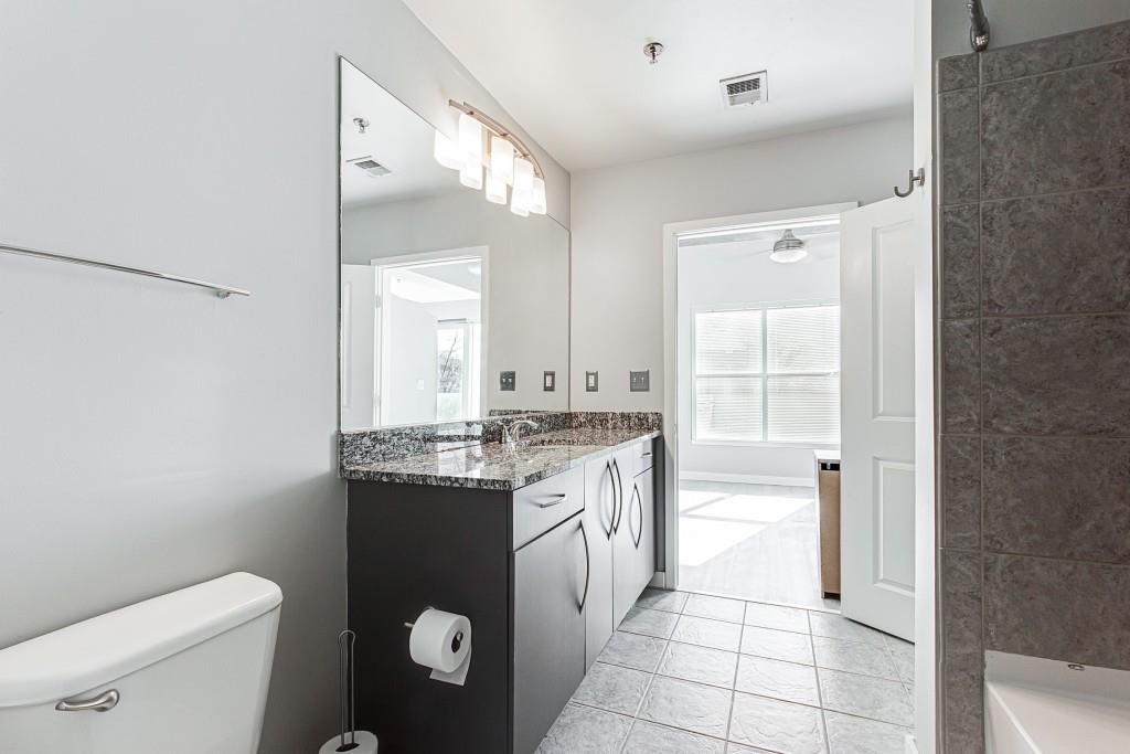 250 Pharr Road Northeast, Unit 216 Atlanta, GA 30305 - Photo 12 of 38 a bathroom with a granite countertop sink a toilet and a mirror