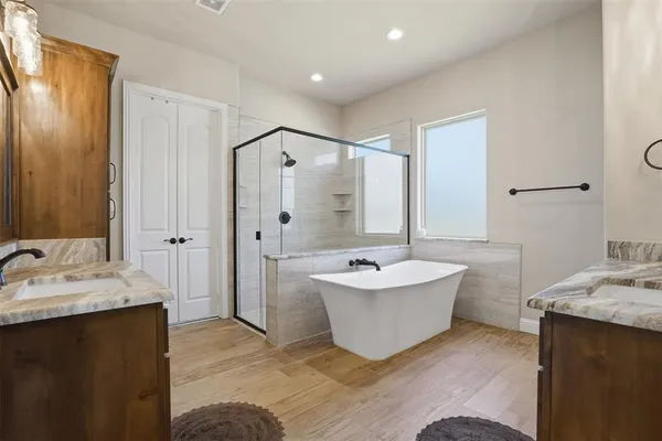 a bathroom with a double vanity sink mirror and bathtub
