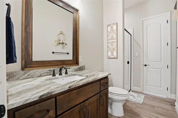a bathroom with a granite countertop sink a toilet and a mirror