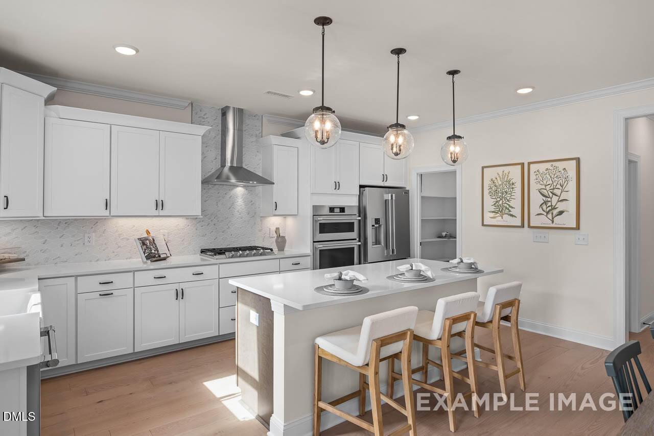 83 Crop Road Angier, NC 27501 - Photo 15 of 40 a kitchen with stainless steel appliances kitchen island granite countertop a sink a stove a refrigerator and white cabinets with wooden floor