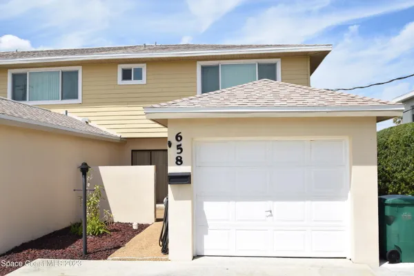 a view of a house with a barbeque and wooden stairs