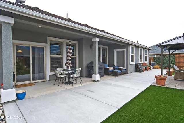 a view of a patio with table and chairs potted plants and floor to ceiling window
