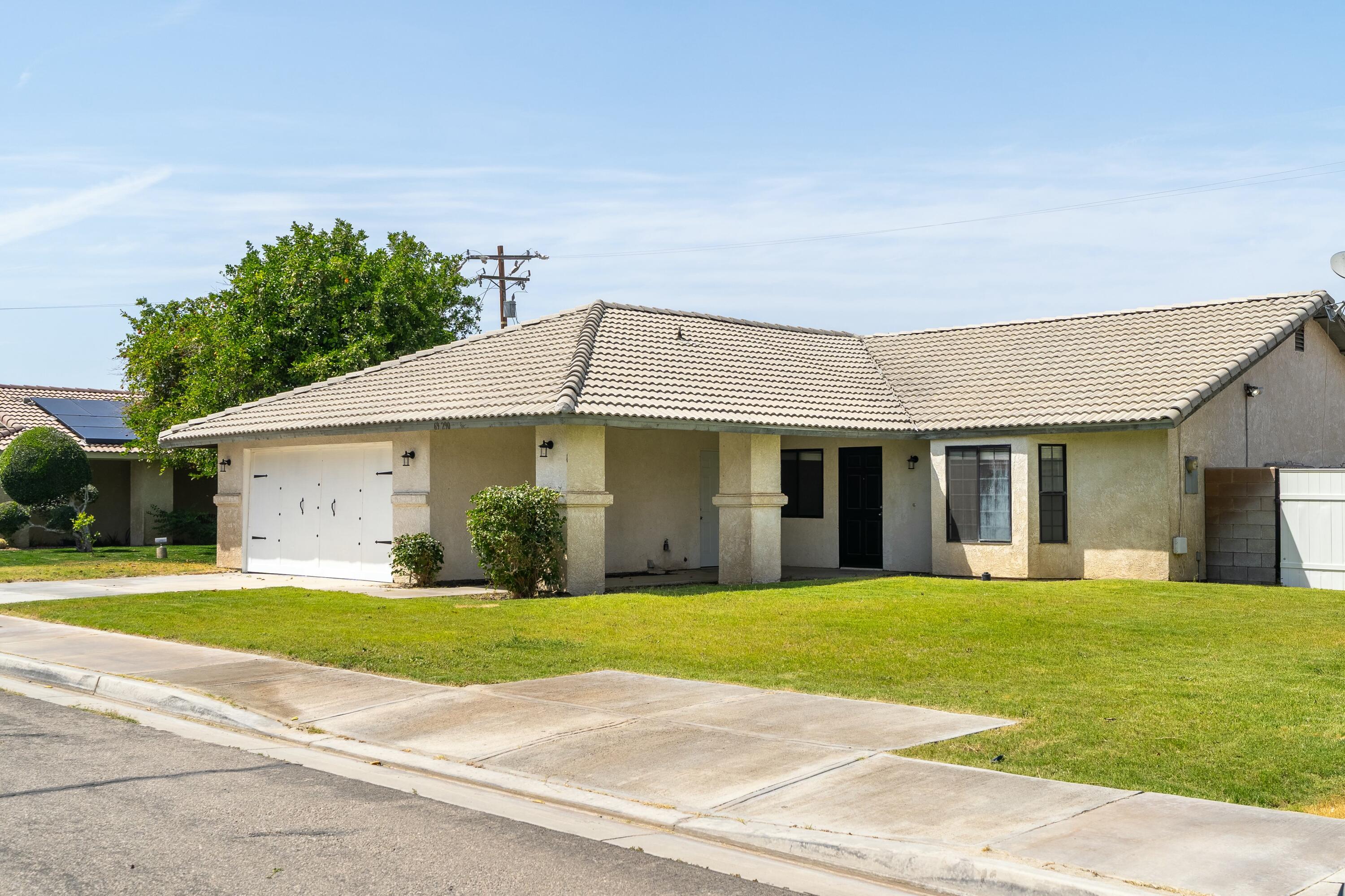69290 El Dobe Road Cathedral City, CA 92234 - Photo 3 of 42 a view of a house with a yard and large trees with wooden fence