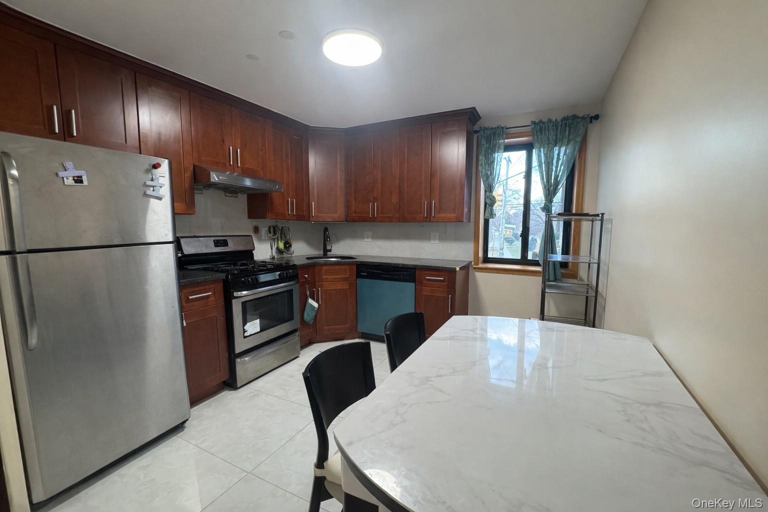 7548 Parsons Boulevard, Unit 2A Queens, NY 11366 - Photo 2 of 5 a kitchen with refrigerator cabinets dining table and chairs