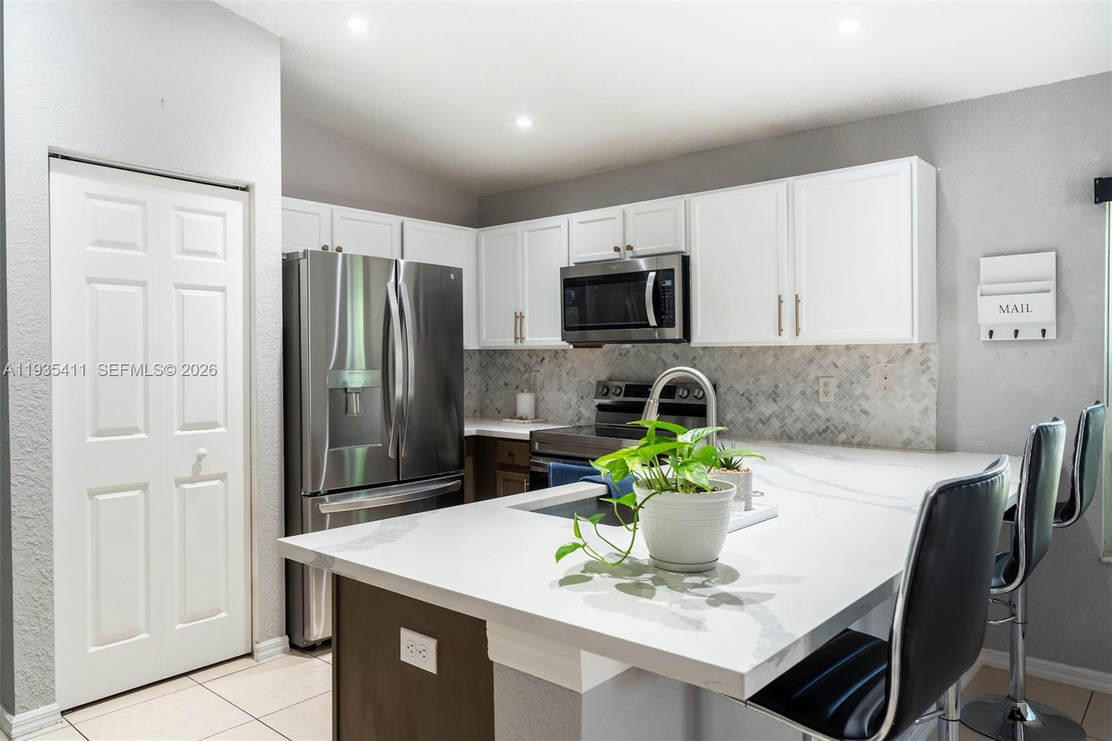 4521 Southwest 124th Terrace Miramar, FL 33027 - Photo 9 of 47 a kitchen with stainless steel appliances a dining table a refrigerator and a stove top oven
