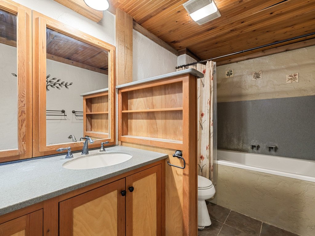 20416 Wilson Road Coupland, TX 78615 - Photo 9 of 39 Rich wood plank ceilings and built-in shelving bring natural warmth to this full bathroom.