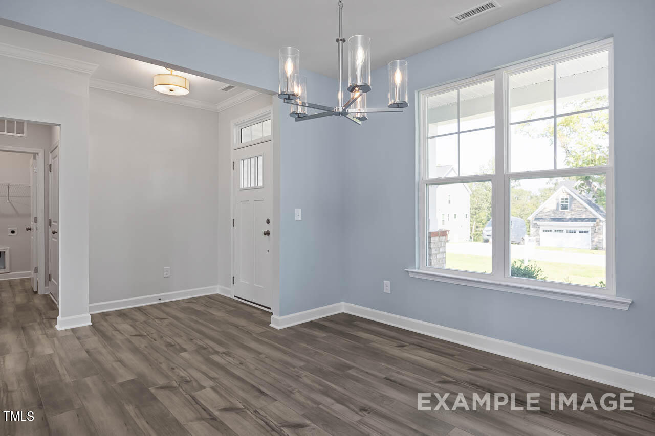 202 Golden Leaf Farms Road Angier, NC 27501 - Photo 4 of 38 an empty room with wooden floor chandelier and windows