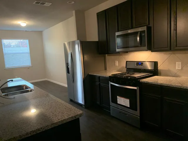 a kitchen with a stove a microwave a sink and cabinets