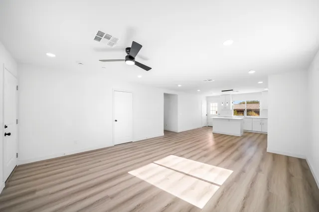 an empty room with a ceiling fan and wooden floor