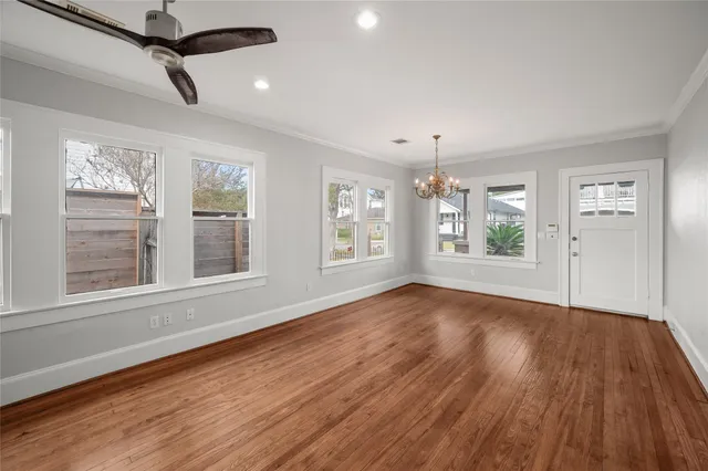 a view of an empty room with wooden floor and a window