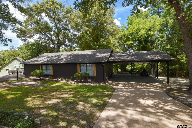 a backyard of a house with table and chairs under an umbrella