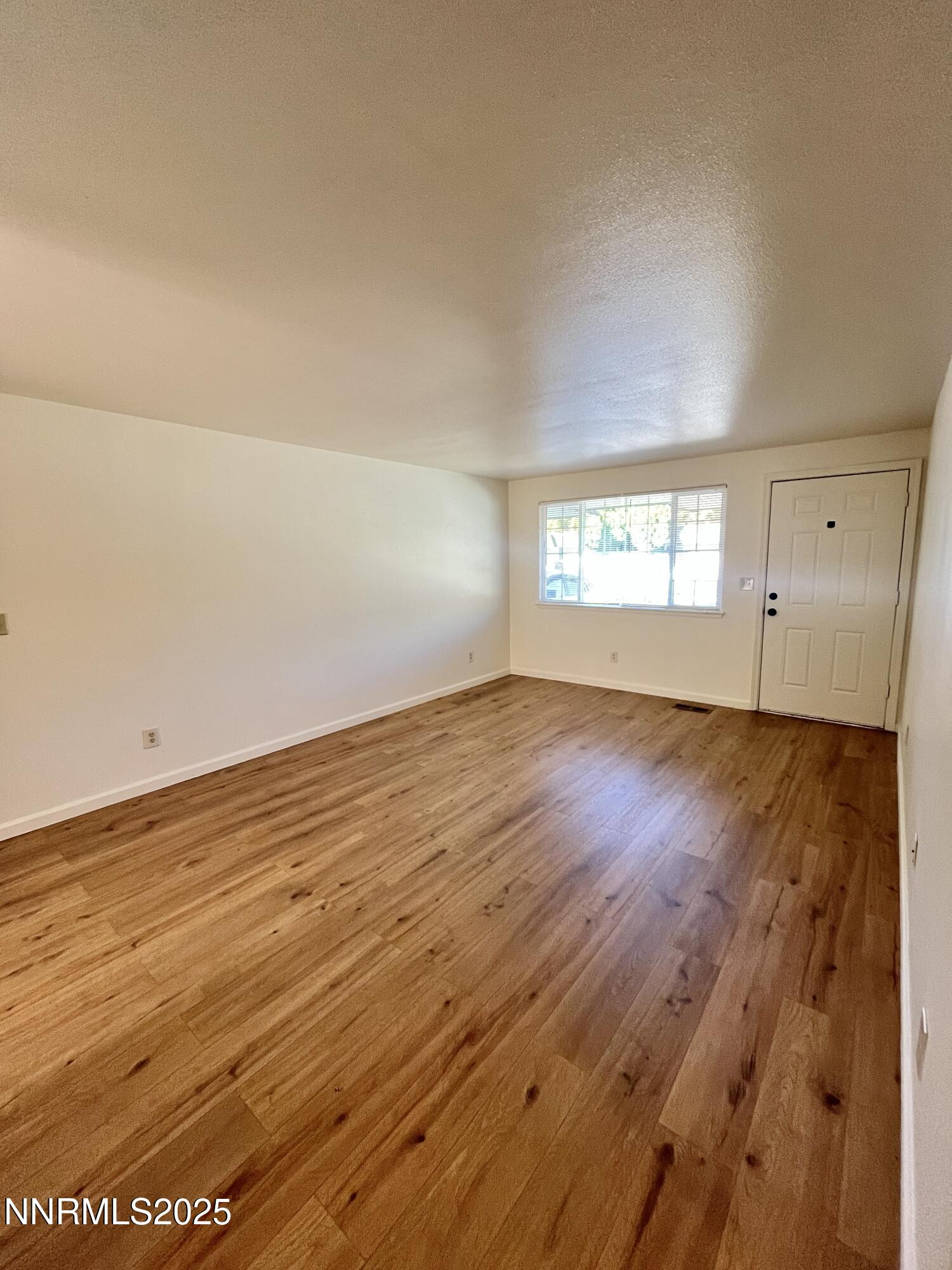 1501 Gault Way Sparks, NV 89431 - Photo 4 of 18 an empty room with wooden floor and windows