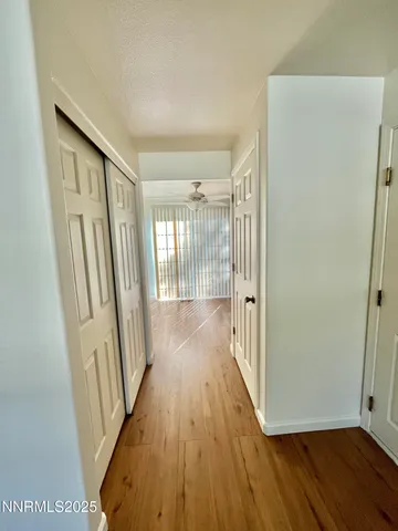 a view of empty room with wooden floor and fan