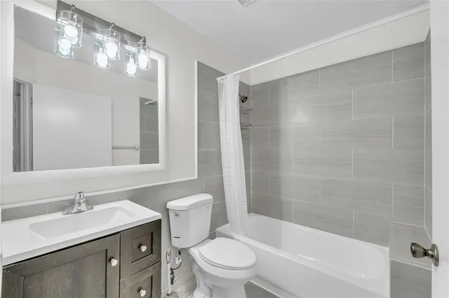 a bathroom with a bathtub shower sink vanity mirror and toilet